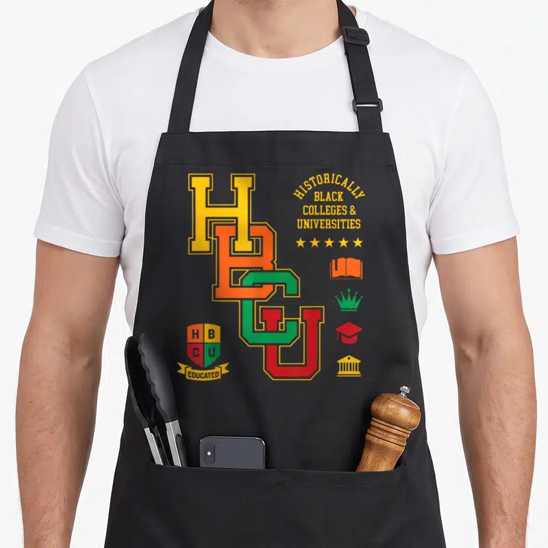 Hbcu jay college apron - Interlocking HBCU letters with shield reading Educated and column of academic symbols — shown on a black cotton canvas apron against a white background
