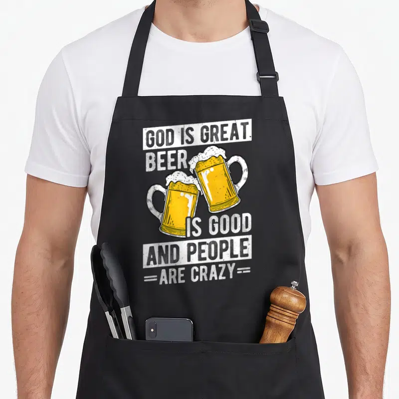 Cool god beer apron - Two yellow beer mugs clinking withGod Is GreatBeer Is GoodAnd People Are Crazytext banners — shown on a black cotton canvas apron against a white background