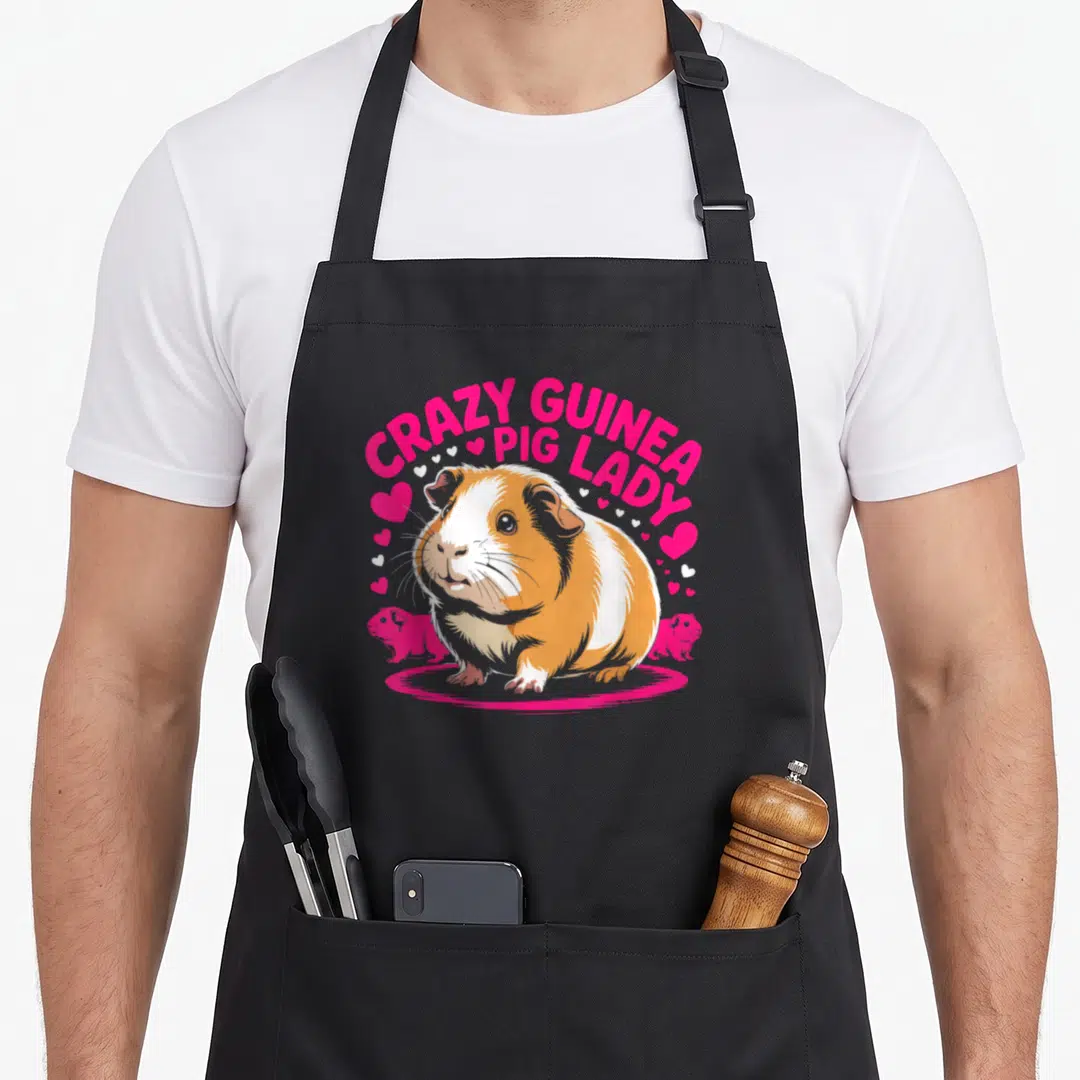 Owner crazy guinea lady apron - Cartoon orange and white guinea pig with pink arched text and scattered hearts — shown on a black cotton canvas apron against a white background