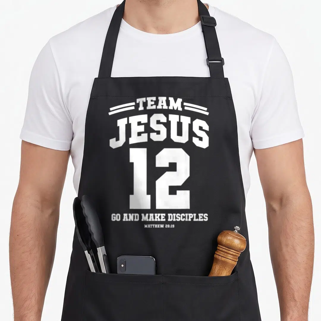 Funny christian christmas apron - White Team Jesus 12 Go And Make Disciples typography on black background — shown on a black cotton canvas apron against a white background