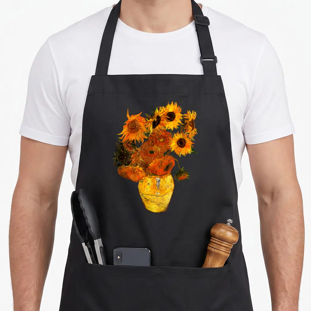 Gogh sunflower apron - Realistic cluster of sunflowers in yellow vase with orange yellow and green tones — shown on a black cotton canvas apron against a white background