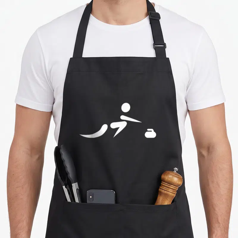 Icon curling addict apron - White silhouette of a sliding person next to a curling stone on grey background — shown on a black cotton canvas apron against a white background