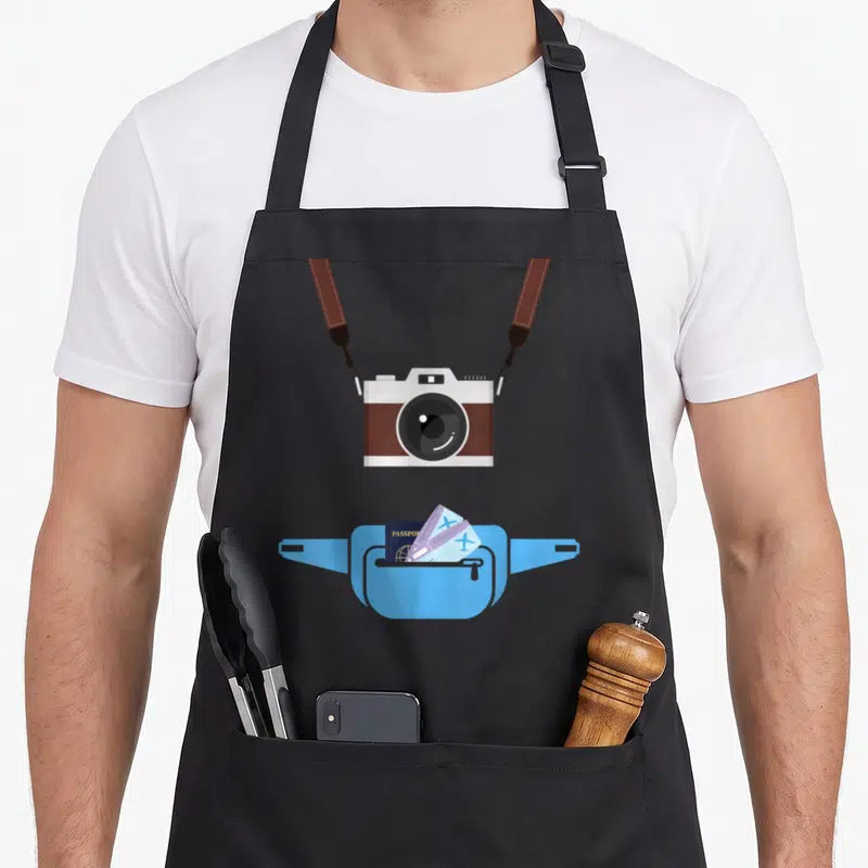 Camera novelty apron - Minimalist camera above blue fanny pack holding PASSPORT and plane tickets — shown on a black cotton canvas apron against a white background