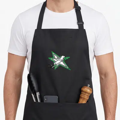 Lone cartoon apron - White bird holding hockey stick inside green-outlined star on black background — shown on a black cotton canvas apron against a white background