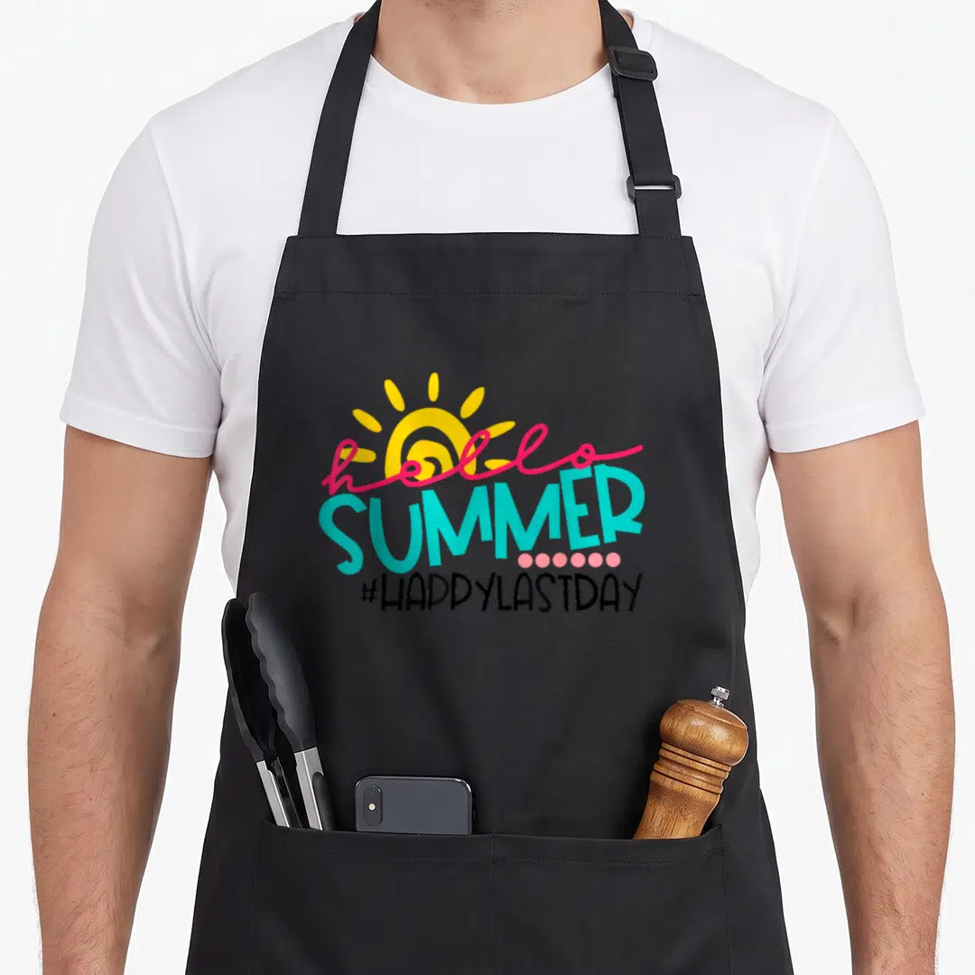School student teacher apron - Yellow sun with pink hello and turquoise SUMMER text above pink dots and black hashtag — shown on a black cotton canvas apron against a white background