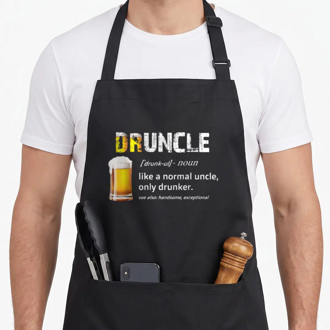 Drunkle funcle apron - DRUNCLE dictionary definition text next to a glass of beer — shown on a black cotton canvas apron against a white background