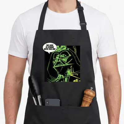 Luck st patrick day aprons - Retro Darth Vader portrait in black and lime green with speech bubble text — shown on a black cotton canvas apron against a white background