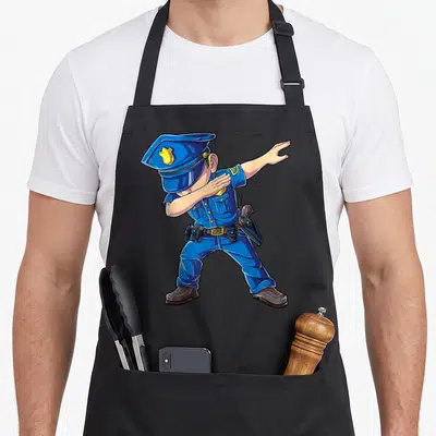 Dabbing police apron - Cartoon police officer in blue uniform performing a dab dance pose with gold badge details — shown on a black cotton canvas apron against a white background