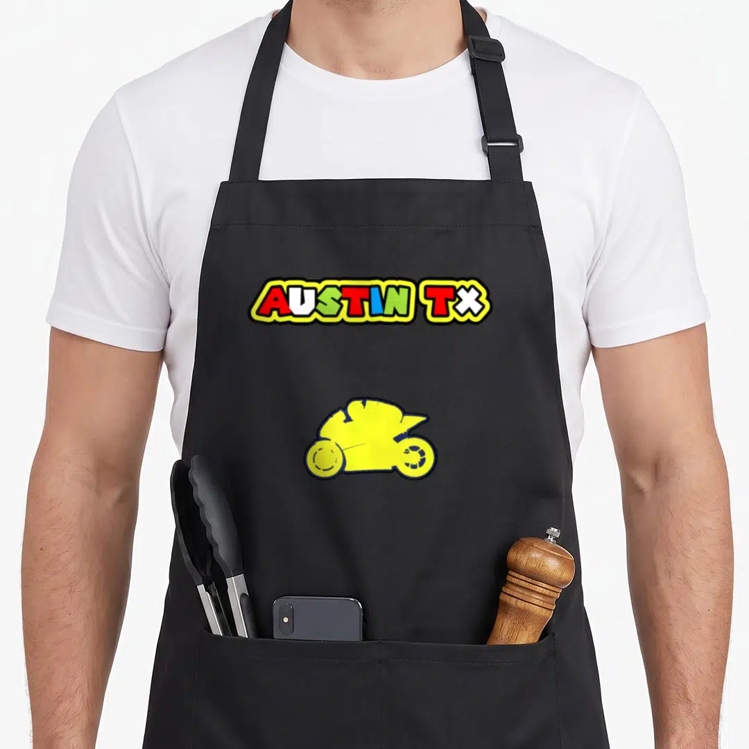 Moto texas aprons - AUSTIN TX multi-colored cartoon text above yellow moped silhouette on black fabric — shown on a black cotton canvas apron against a white background