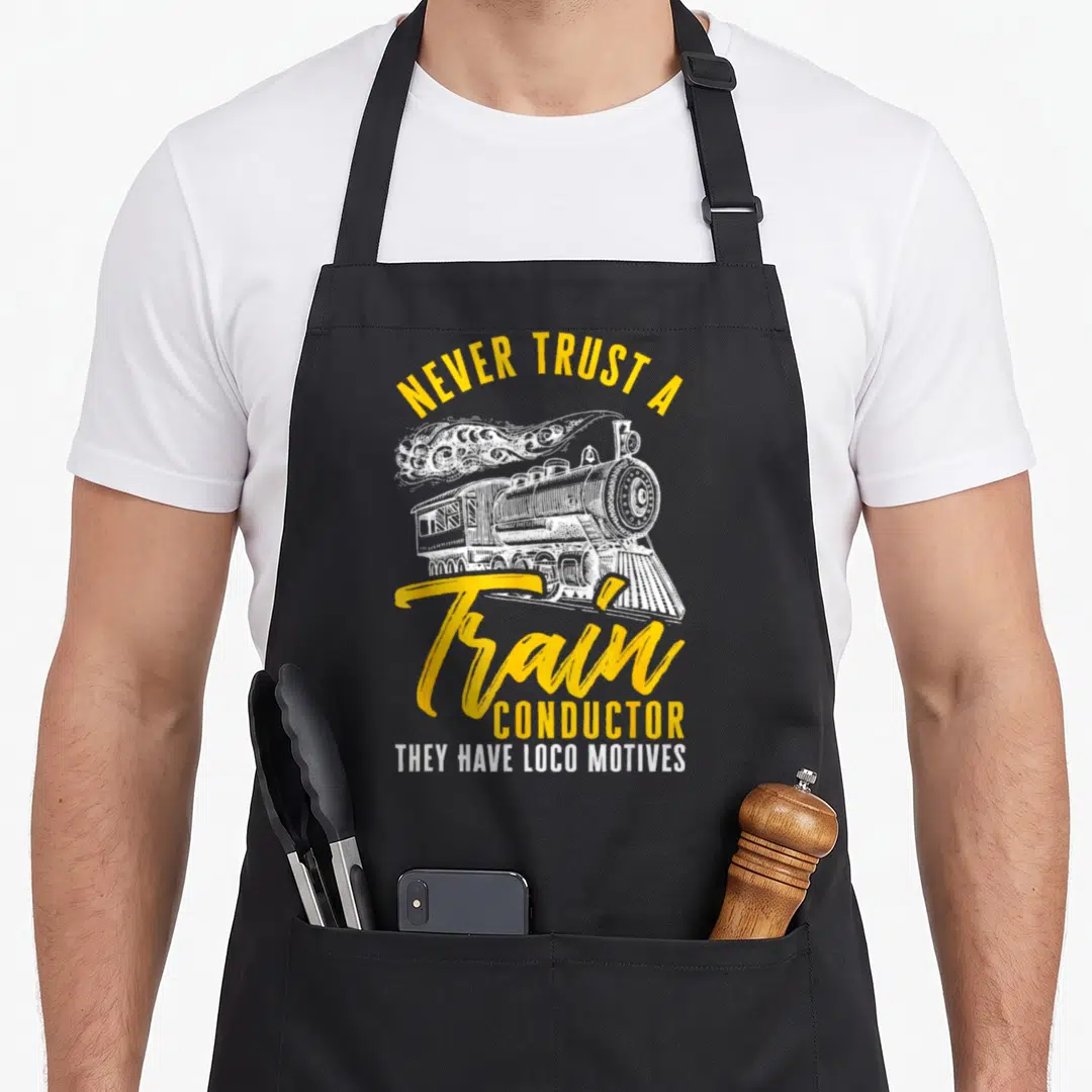 Motive loco apron - Steam locomotive line art with yellow text Never Trust a Train Conductor They Have Loco Motives — shown on a black cotton canvas apron against a white background