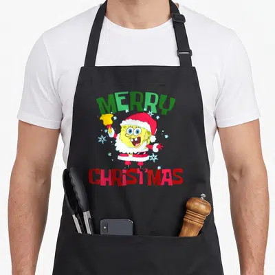 Squarepant merry christmas apron - SpongeBob in Santa suit holding bell with Merry Christmas text and snowflakes — shown on a black cotton canvas apron against a white background