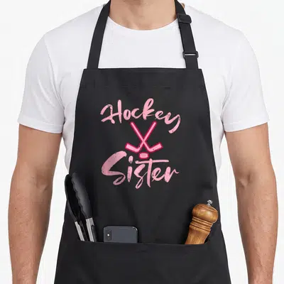 Sister hockey ice apron - Pink Hockey Sister text with crossed sticks and puck centered on chest — shown on a black cotton canvas apron against a white background