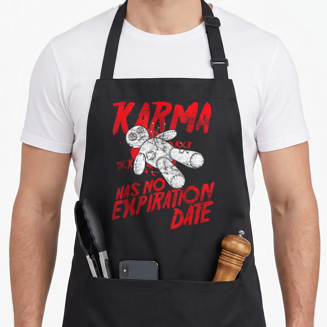 Voodoo halloween apron - Distressed red text surrounding a white voodoo doll with pins stuck in its back — shown on a black cotton canvas apron against a white background