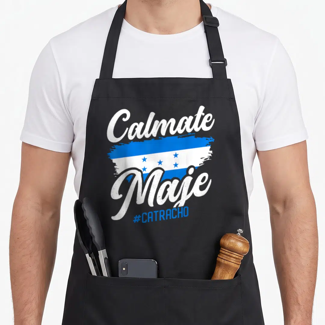 Baleada honduran apron - Calmate Maje text with blue white brushstroke flag and #CATRACHO hashtag — shown on a black cotton canvas apron against a white background