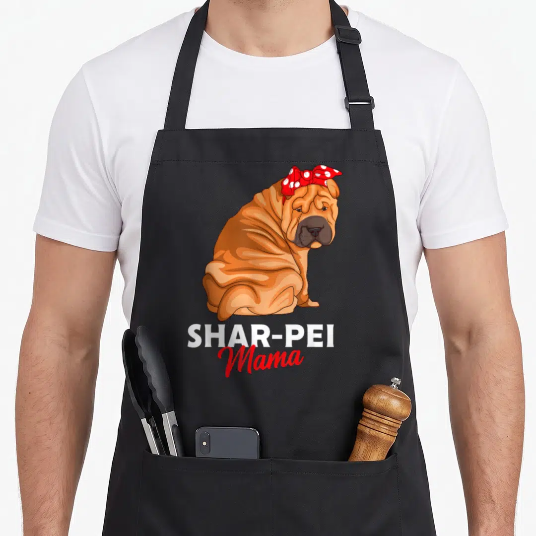 Shar dog apron - Cartoon tan Shar-Pei with red polka dot bow and text SHAR-PEI Mama — shown on a black cotton canvas apron against a white background