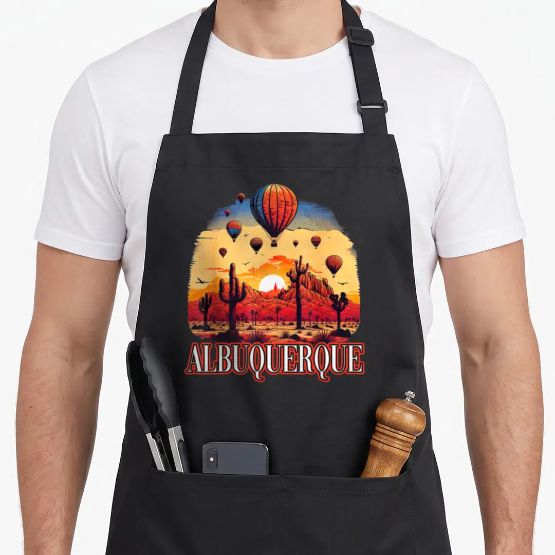 Hot mexico apron - RetroPRINT of hot air balloons over red mountains with ALBUQUERQUE text at bottom — shown on a black cotton canvas apron against a white background