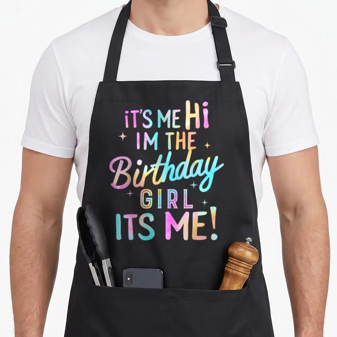 Occasion birthday apron - Tie-dye text IT'S ME Hi IM THE Birthday GIRL with white sparkles — shown on a black cotton canvas apron against a white background