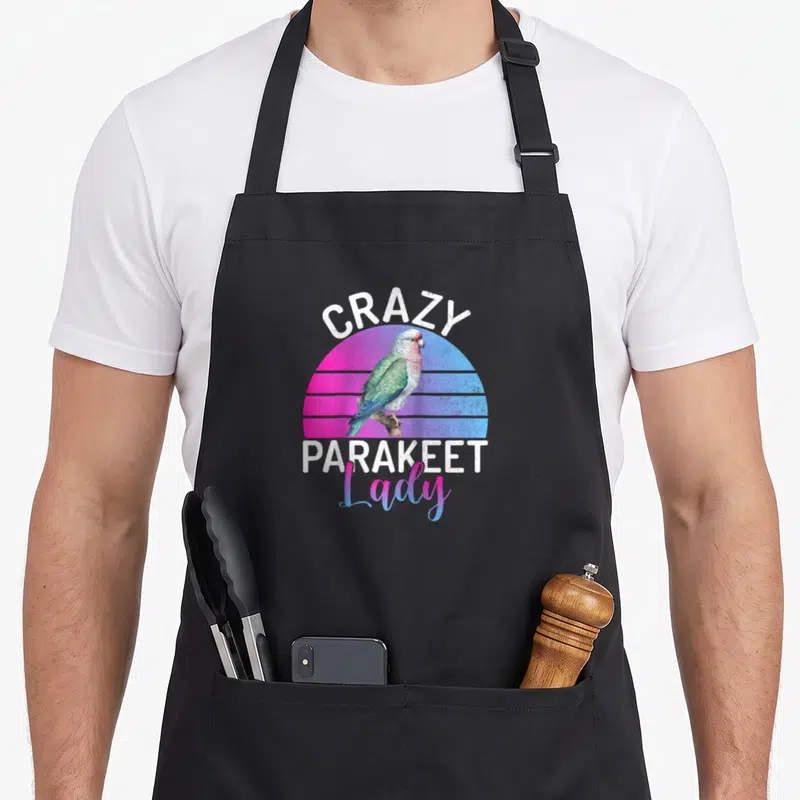 Funny parakeet baseball apron - Retro parakeet on branch with pink blue gradient sun and white text CRAZY PARAKEET Lady — shown on a black cotton canvas apron against a white background