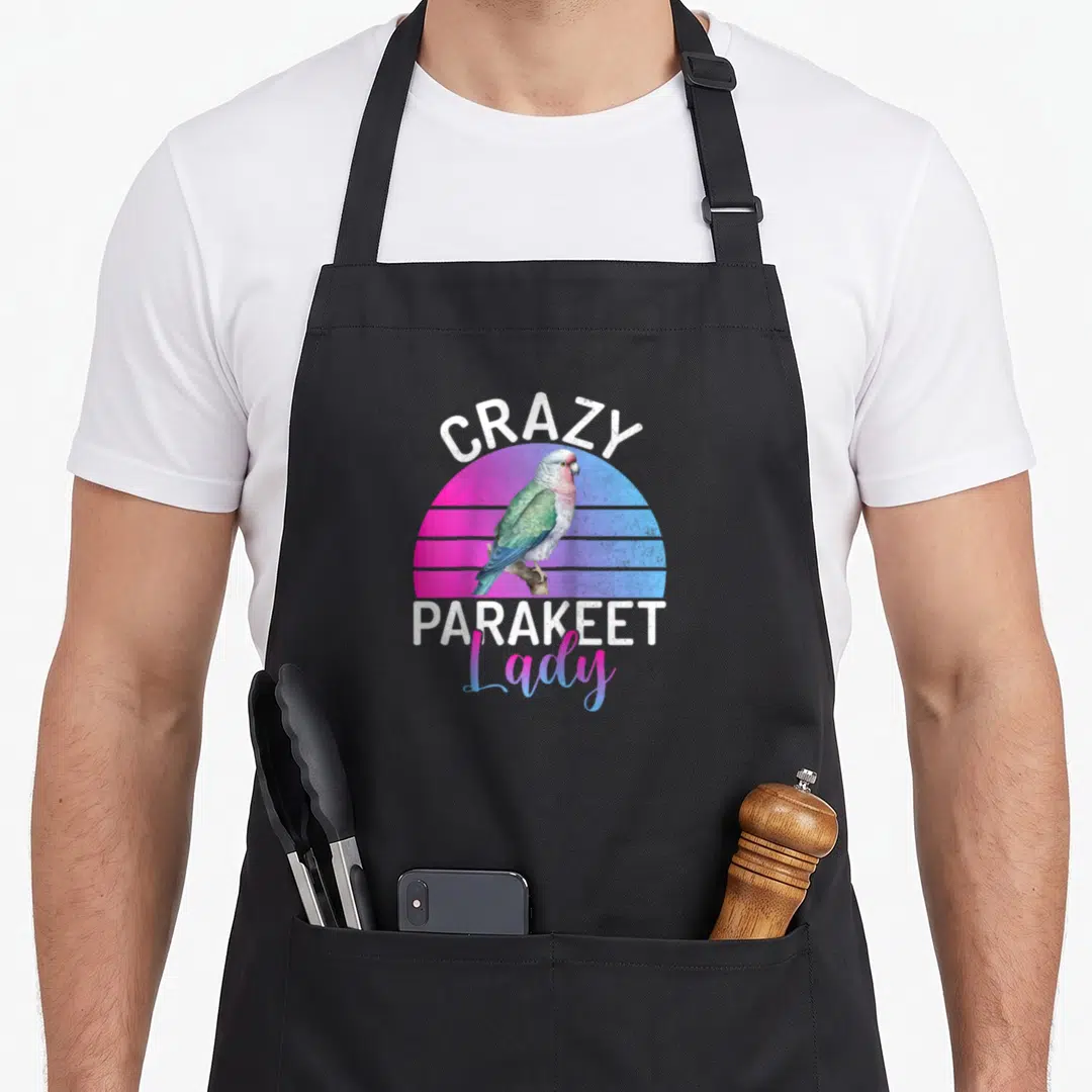 Funny parakeet baseball apron - Retro parakeet on branch with pink blue gradient sun and white text CRAZY PARAKEET Lady — shown on a black cotton canvas apron against a white background