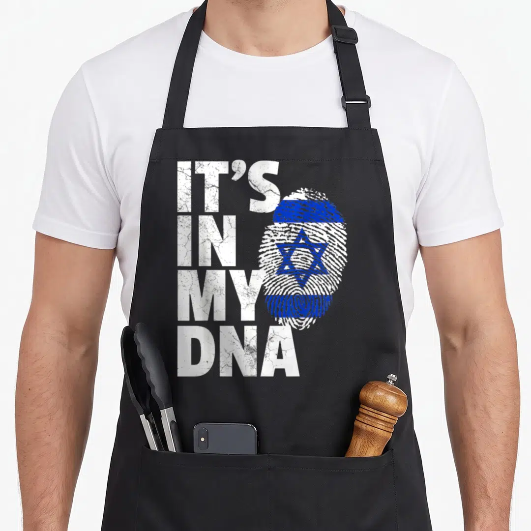 Israeli pride apron - IT'S IN MY DNA text next to a fingerprint shaped as the Israeli flag in blue and white — shown on a black cotton canvas apron against a white background