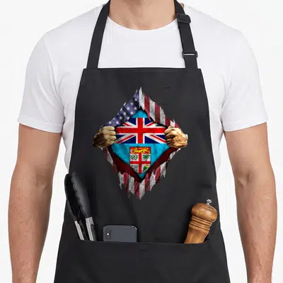 Fijian american flag apron - Two hands tearing distressed USA flag to reveal Fiji flag, realistic blue red white art — shown on a black cotton canvas apron against a white background
