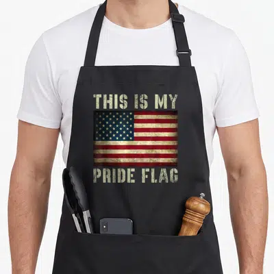 Pride flag 4th of july apron - Distressed USA flag centered between beige THIS IS MY PRIDE FLAG text — shown on a black cotton canvas apron against a white background