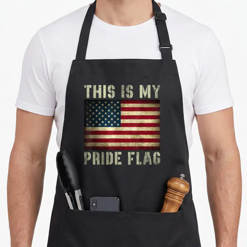 Pride flag 4th of july apron - Distressed USA flag centered between beige THIS IS MY PRIDE FLAG text — shown on a black cotton canvas apron against a white background