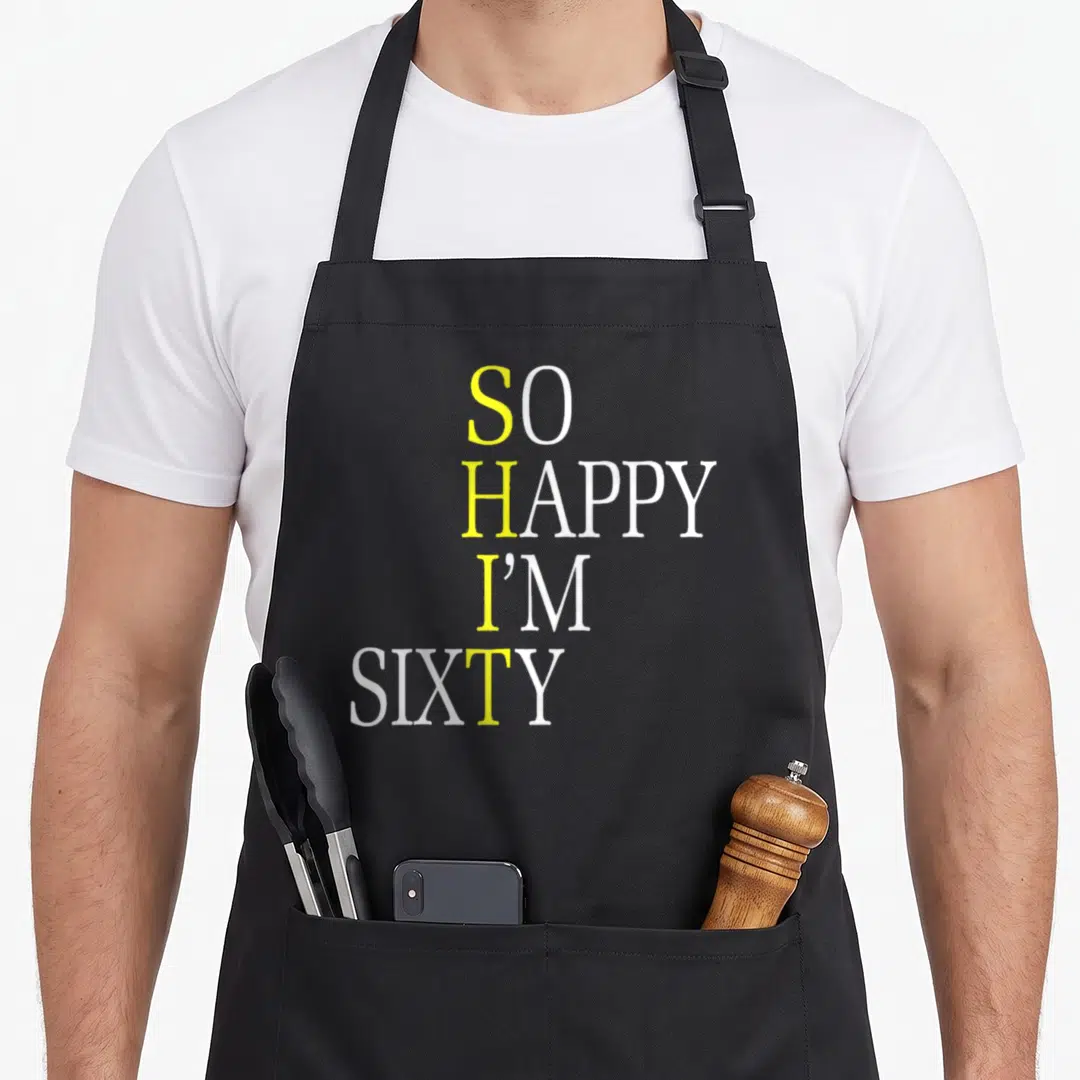 Sixty joke apron - Yellow and white text reading So Happy I'm Sixty stacked vertically — shown on a black cotton canvas apron against a white background