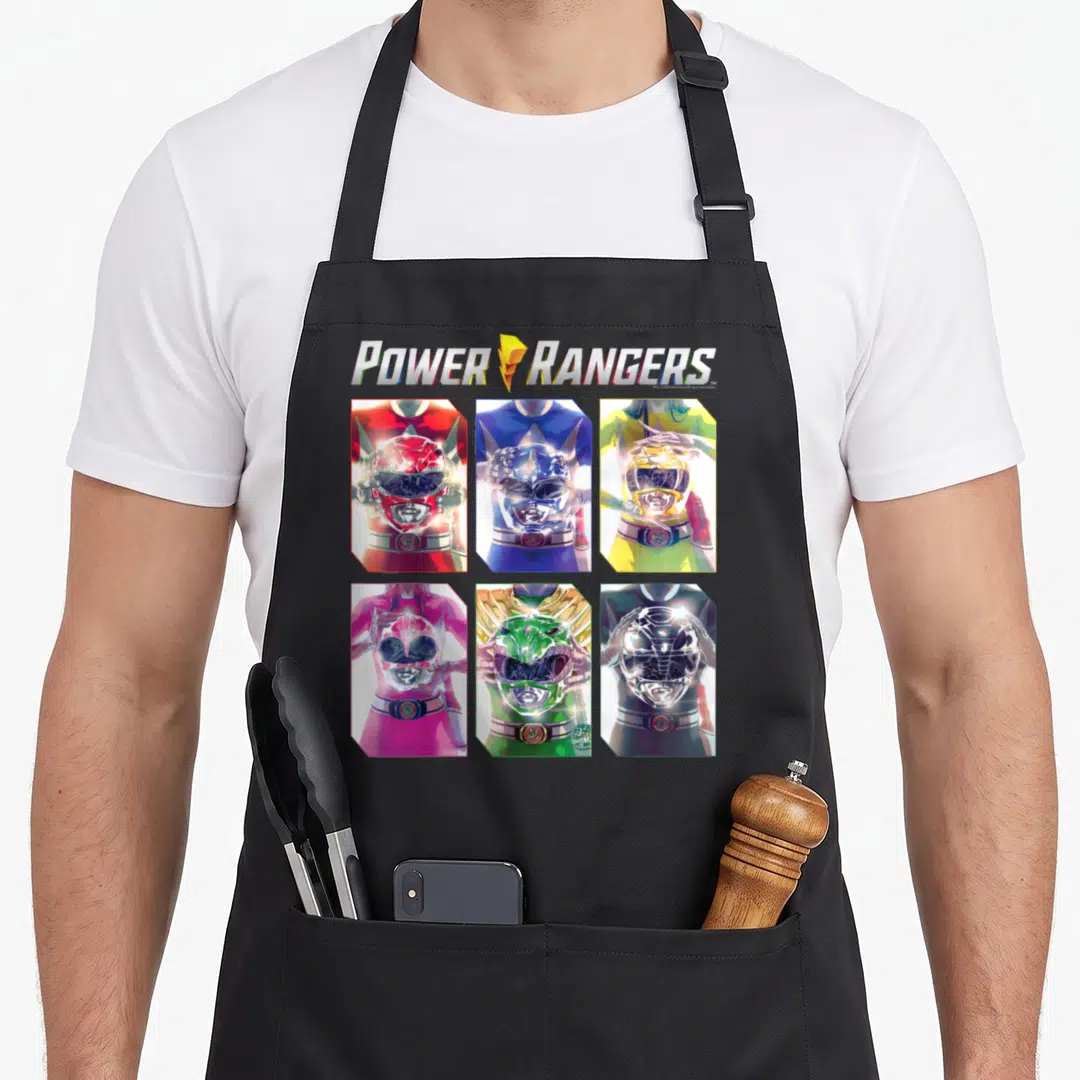 Helmet character aprons - Six Power Rangers in red, blue, yellow, pink, green, and black holding helmets in a photo — shown on a black cotton canvas apron against a white background
