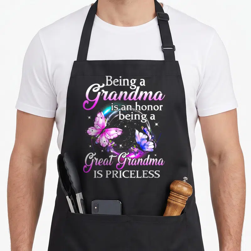 Honor great grandma apron - Two pink and blue watercolor butterflies inside a white circle with text about being — shown on a black cotton canvas apron against a white background