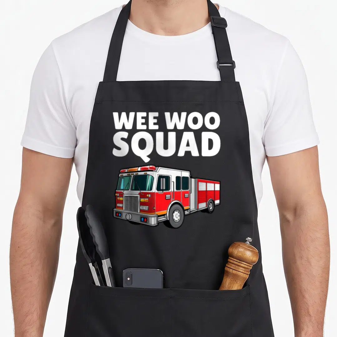 Fireman truck apron - WEE WOO SQUAD text above red and white cartoon fire truck illustration — shown on a black cotton canvas apron against a white background