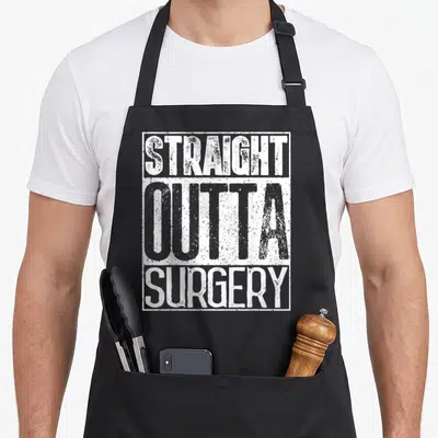 Straight surgeon apron - Distressed white text reading STRAIGHT OUTTA SURGERY stacked in three lines inside — shown on a black cotton canvas apron against a white background