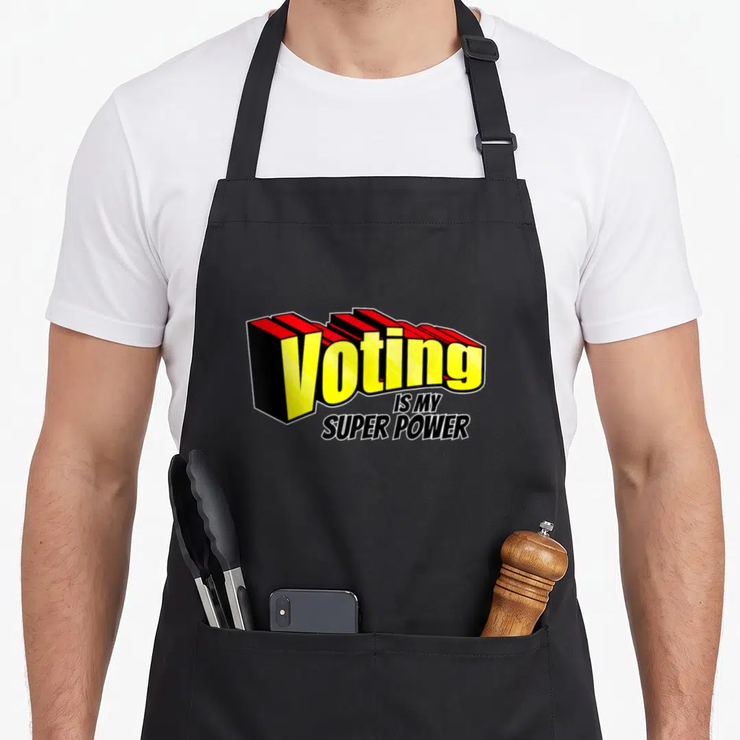 Election political aprons - Yellow 3D text reading Voting is My Super Power with red depth and black lower lines — shown on a black cotton canvas apron against a white background