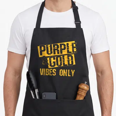 School football apron - Yellow blocks with grey text reading purple and gold vibes only on grey background — shown on a black cotton canvas apron against a white background