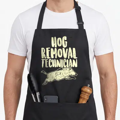 Removal hunter apron - Distressed beige text HOG REMOVAL TECHNICIAN above a running wild boar illustration — shown on a black cotton canvas apron against a white background