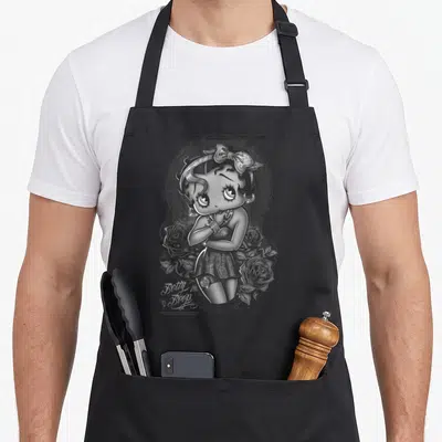 Cartoon rose apron - Betty Boop in decorative frame with roses and script text in grey white black — shown on a black cotton canvas apron against a white background