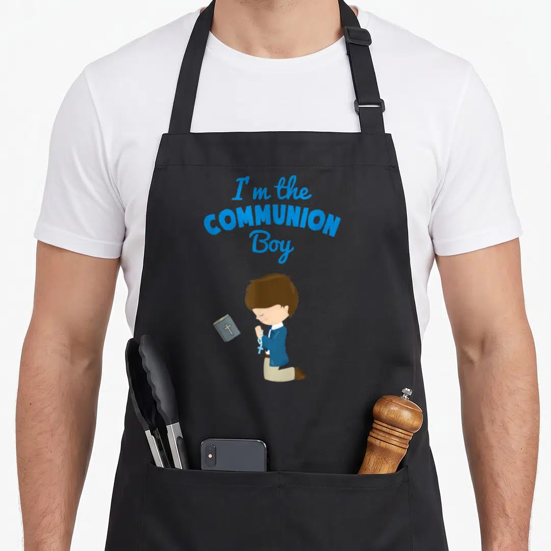 Costume son communion aprons - Cartoon boy kneeling with rosary and floating prayer book under blue text — shown on a black cotton canvas apron against a white background