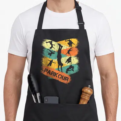 Silhouette parkour apron - Six grey parkour silhouettes on yellow orange teal brushstrokes with PARKOUR text — shown on a black cotton canvas apron against a white background