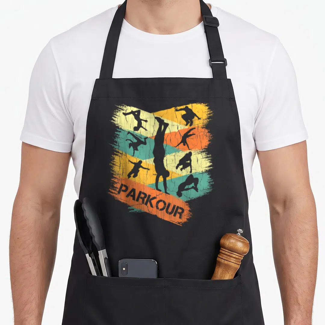 Silhouette parkour apron - Six grey parkour silhouettes on yellow orange teal brushstrokes with PARKOUR text — shown on a black cotton canvas apron against a white background