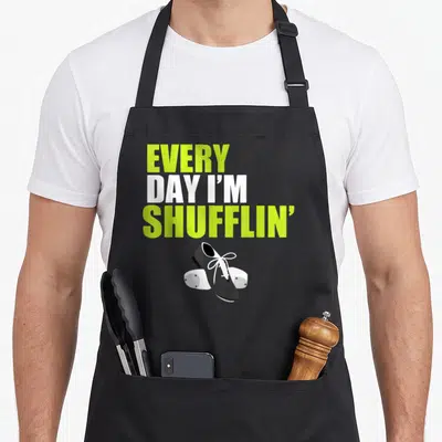 Shufflin dancing apron - Stacked lime and white text reading Every Day I'm Shufflin above a black tap shoe — shown on a black cotton canvas apron against a white background