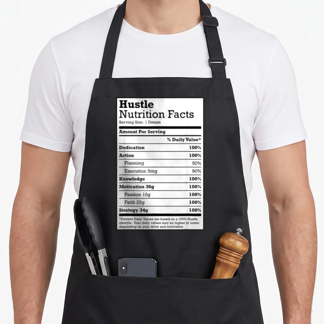 Nutrition christmas apron - Black and white nutrition label listing hustle ingredients like dedication action — shown on a black cotton canvas apron against a white background