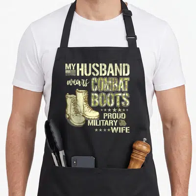 Husband personalized dog apron - Beige combat boots and dog tags with My Husband Wears Combat Boots text — shown on a black cotton canvas apron against a white background