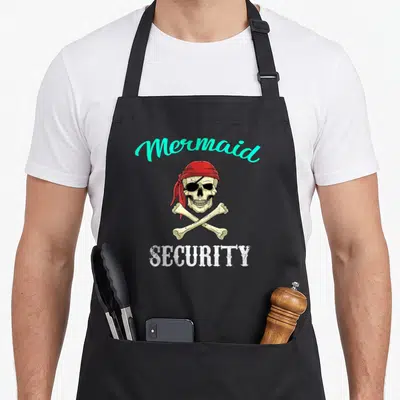 Pirate mermaid apron - Cartoon skull in red bandana with crossbones, Mermaid SECURITY text in turquoise and white — shown on a black cotton canvas apron against a white background