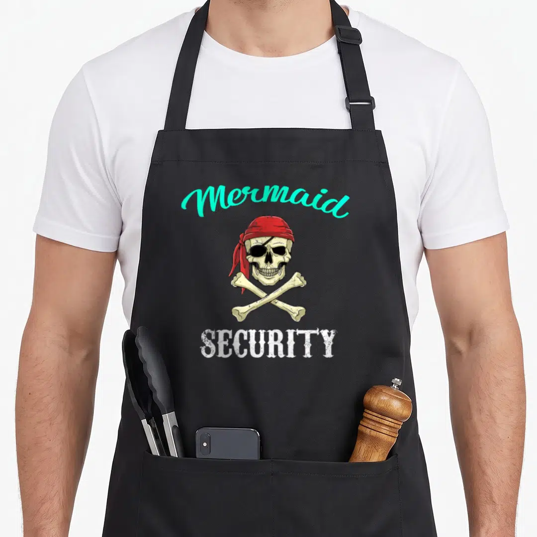 Pirate mermaid apron - Cartoon skull in red bandana with crossbones, Mermaid SECURITY text in turquoise and white — shown on a black cotton canvas apron against a white background