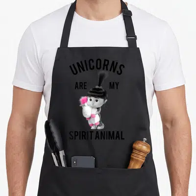 Despicable animal apron - Girl holding pink unicorn plush with text unicorns are my spirit animal — shown on a black cotton canvas apron against a white background