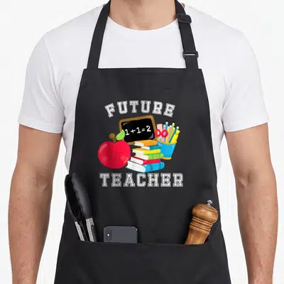 Future costume teacher apron - Cartoon red apple, chalkboard with 1+1=2, stacked books, and pencil cup framed by white — shown on a black cotton canvas apron against a white background
