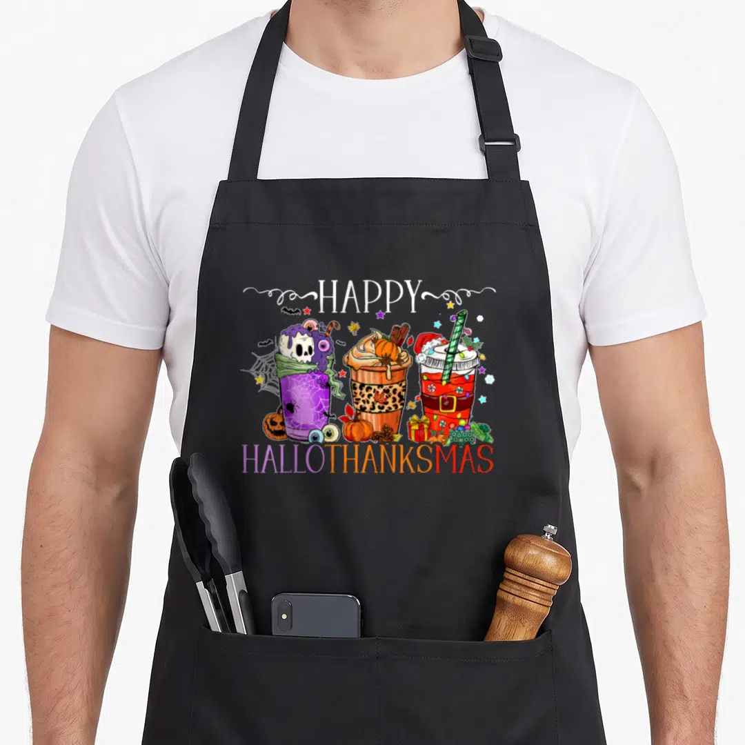 Hallothanksmas thanksgiving apron - Three drinks in purple orange red white with HAPPY HALLOTHANKSMAS text and holiday — shown on a black cotton canvas apron against a white background