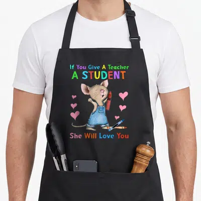 Mouse teacher apron - Cartoon brown mouse holding red crayon with pink hearts and blue crayon below rainbow text — shown on a black cotton canvas apron against a white background