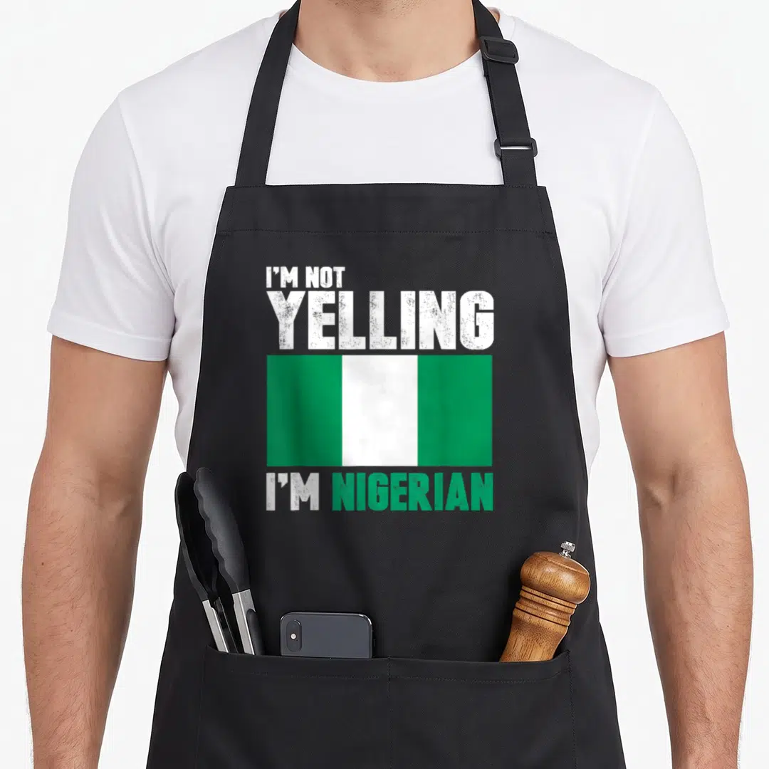 Yelling nigerian apron - Distressed text I'm Not Yelling I'm Nigerian above and below a green and white flag — shown on a black cotton canvas apron against a white background