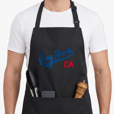 Beach king apron - Long Beach script text in blue with red CA abbreviation below — shown on a black cotton canvas apron against a white background